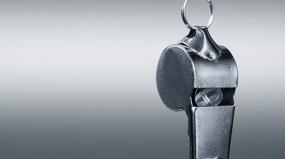 A silver whistle against a grey background